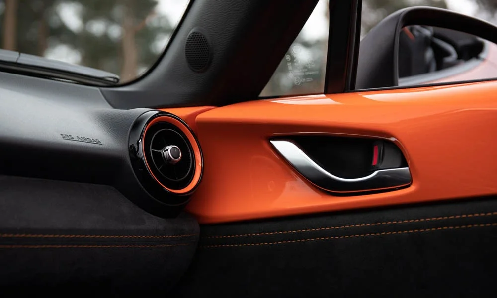 Фото Mazda MX-5 — дверная карта. Внутренняя панель двери: сочетание материалов и компоновка управления в тёмной гамме Mazda MX-5 — дверная карта