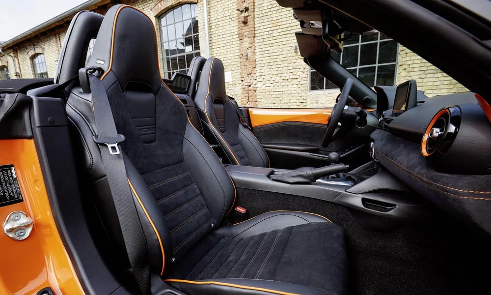Фото Mazda MX-5 — интерьер, фото 4. Интерьер с тёмной отделкой — видно сочетание материалов панели и кресел. Светлая гамма зрительно расширяет салон, тёмная — практичнее в уходе Mazda MX-5 — интерьер, фото 4