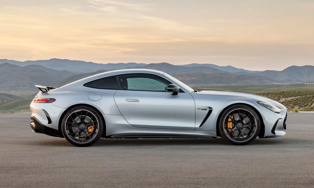 Фото Mercedes-Benz AMG GT (2024) — вид сбоку, фото 2. Профиль в серебристом цвете: соотношение колёсной базы и свесов. Длинная база — простор второго ряда; короткие свесы упрощают парковку Mercedes-Benz AMG GT (2024) — вид сбоку, фото 2