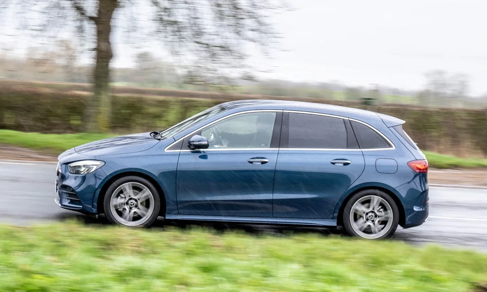 Фото Mercedes-Benz B-Class (2024) — вид сбоку, фото 3. Профиль в синем цвете: соотношение колёсной базы и свесов. Хромированные или чёрные молдинги окон отличают комплектации Mercedes-Benz B-Class (2024) — вид сбоку, фото 3