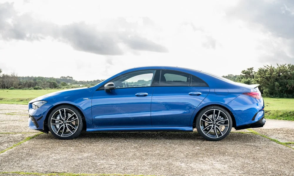 Фото Mercedes-Benz CLA (2024) — вид сбоку. Сбоку читаются линия остекления и характер выштамповок на синем кузове. Хромированные или чёрные молдинги окон отличают комплектации Mercedes-Benz CLA (2024) — вид сбоку