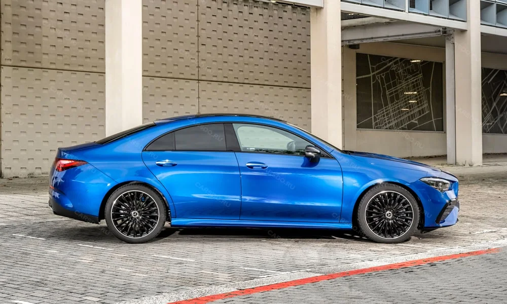 Фото Mercedes-Benz CLA (2024) — вид сбоку, фото 3. Синий кузов в профиль — пропорции, высота посадки и дизайн дисков. Хромированные или чёрные молдинги окон отличают комплектации Mercedes-Benz CLA (2024) — вид сбоку, фото 3