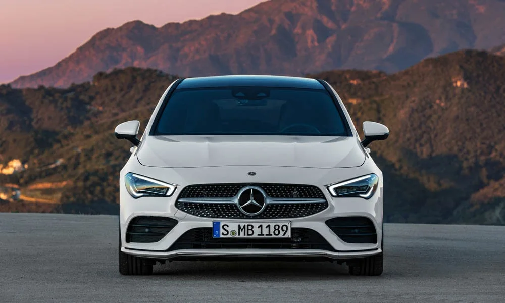 Фото Mercedes-Benz CLA — вид спереди, фото 11. Кузов в белом цвете: рисунок оптики и решётки задаёт узнаваемое «лицо» модели Mercedes-Benz CLA — вид спереди, фото 11