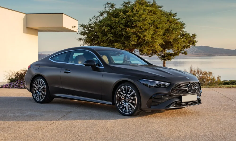 Фото Mercedes-Benz CLE (2024) — вид спереди. Передок в чёрном исполнении — крупная светотехника и выразительный бампер. Рисунок ходовых огней — подпись модели, по нему её узнают в потоке Mercedes-Benz CLE (2024) — вид спереди