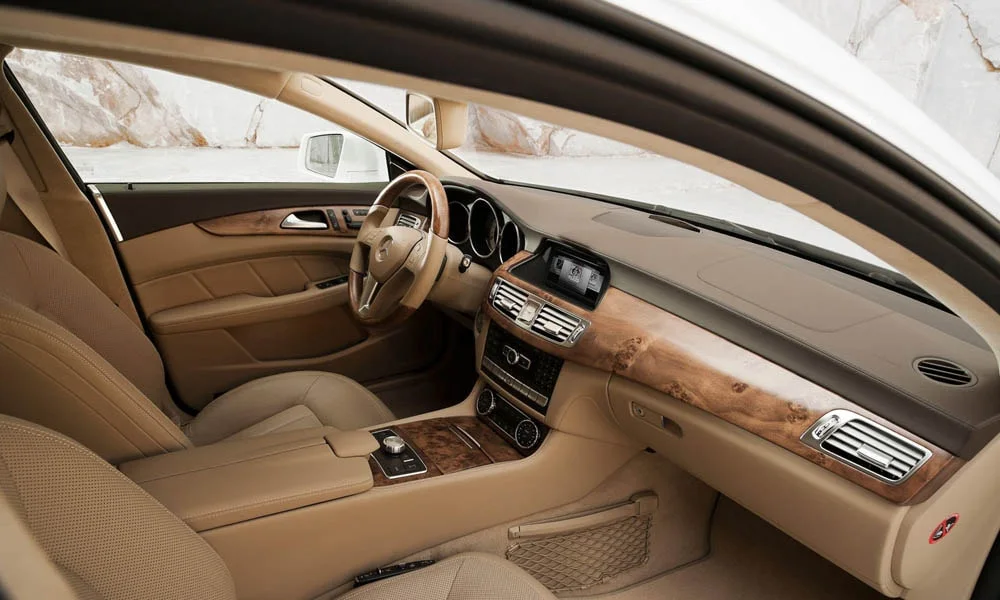 Фото Mercedes-Benz CLS — интерьер. Салон в светлой бежевой отделке: архитектура передней панели, консоль и кресла. Уровень отделки читается по стыкам панелей и мягким поверхностям в зонах касания Mercedes-Benz CLS — интерьер
