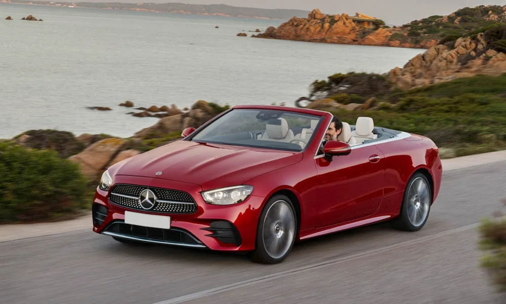 Фото Mercedes-Benz E-Class — вид спереди, фото 19. Кузов в красном цвете: рисунок оптики и решётки задаёт узнаваемое «лицо» модели. Рисунок ходовых огней — подпись модели, по нему её узнают в потоке Mercedes-Benz E-Class — вид спереди, фото 19