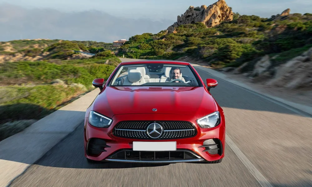 Фото Mercedes-Benz E-Class — вид спереди, фото 20. Кузов в красном цвете: рисунок оптики и решётки задаёт узнаваемое «лицо» модели. Рисунок ходовых огней — подпись модели, по нему её узнают в потоке Mercedes-Benz E-Class — вид спереди, фото 20