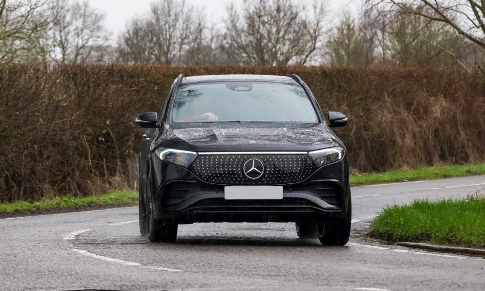 Фото Mercedes-Benz EQA (2024) — вид спереди, фото 5. Чёрный кузов, строгая симметрия оптики — базовый ракурс знакомства с дизайном. Рисунок ходовых огней — подпись модели, по нему её узнают в потоке Mercedes-Benz EQA (2024) — вид спереди, фото 5