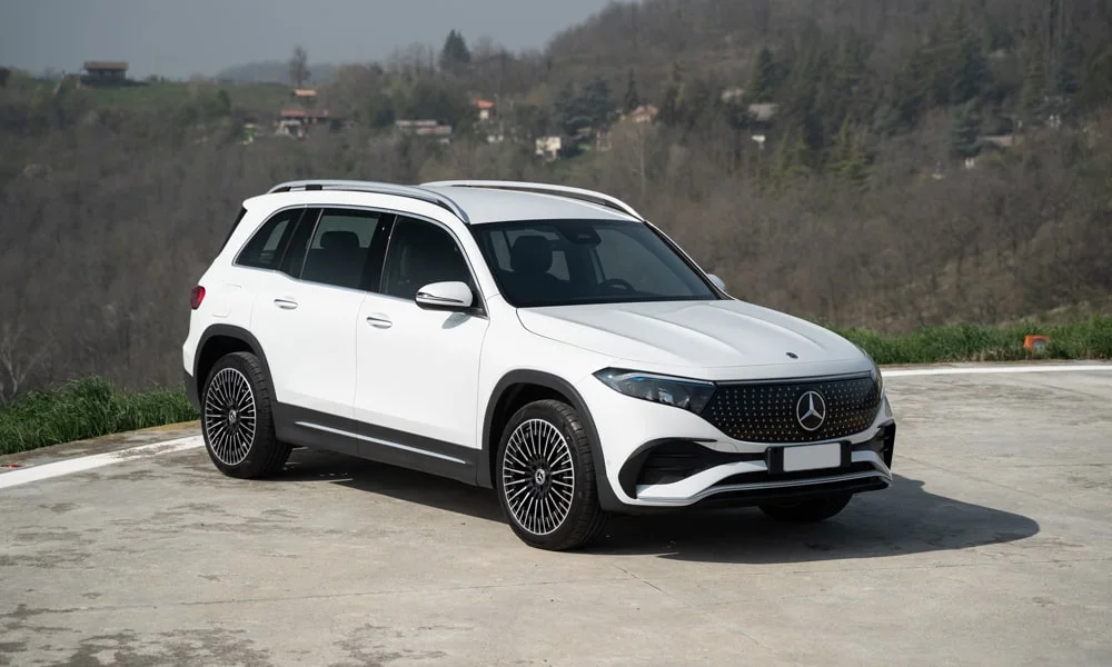Фото Mercedes-Benz EQB (2024) — вид спереди, фото 4. Передок в белом исполнении — крупная светотехника и выразительный бампер. Рисунок ходовых огней — подпись модели, по нему её узнают в потоке Mercedes-Benz EQB (2024) — вид спереди, фото 4