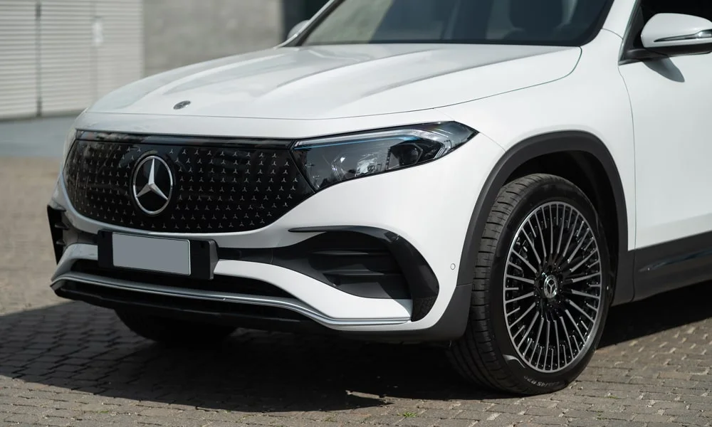 Фото Mercedes-Benz EQB (2024) — вид спереди, фото 5. Передок в белом исполнении — крупная светотехника и выразительный бампер. Рисунок ходовых огней — подпись модели, по нему её узнают в потоке Mercedes-Benz EQB (2024) — вид спереди, фото 5