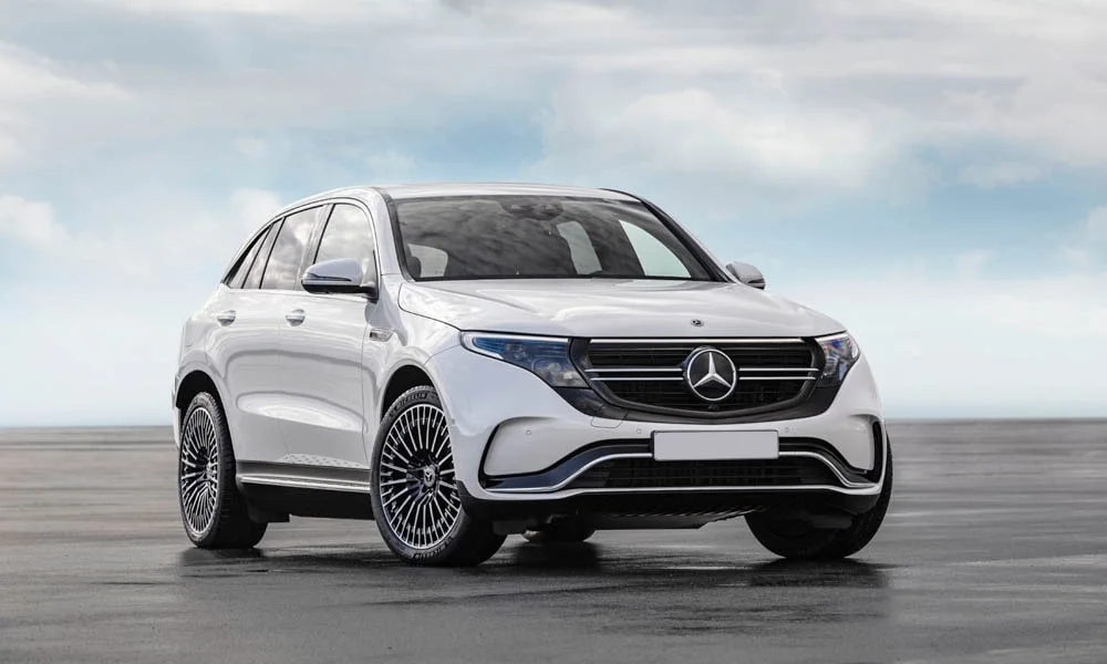 Фото Mercedes-Benz EQC (2024) — вид спереди. Кузов в белом цвете: рисунок оптики и решётки задаёт узнаваемое «лицо» модели. Рисунок ходовых огней — подпись модели, по нему её узнают в потоке Mercedes-Benz EQC (2024) — вид спереди
