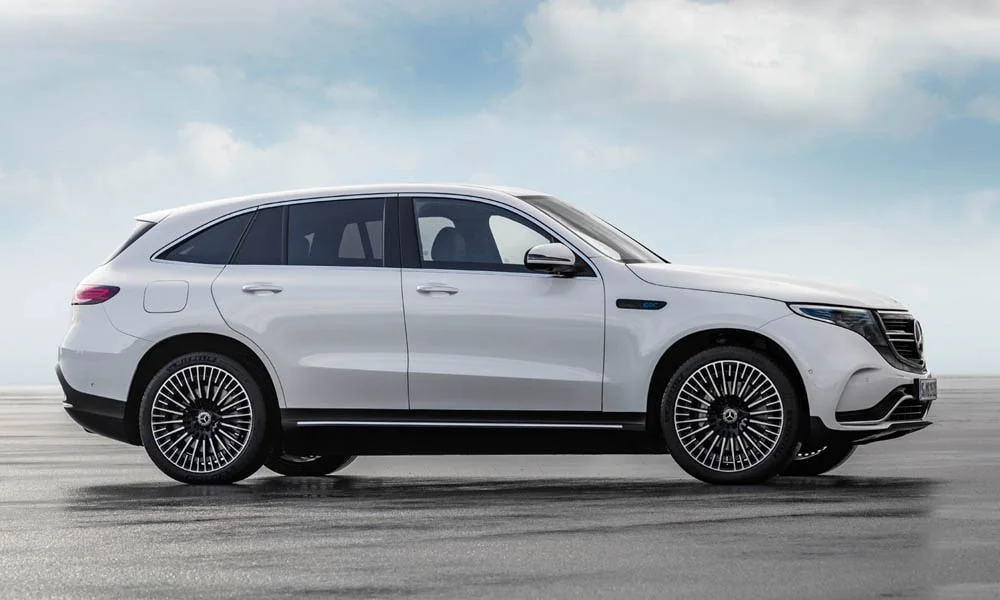 Фото Mercedes-Benz EQC (2024) — вид сбоку. Сбоку читаются линия остекления и характер выштамповок на белом кузове. Хромированные или чёрные молдинги окон отличают комплектации Mercedes-Benz EQC (2024) — вид сбоку