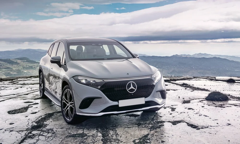 Фото Mercedes-Benz EQS SUV (2024) — вид спереди. Кузов в серебристом цвете: рисунок оптики и решётки задаёт узнаваемое «лицо» модели Mercedes-Benz EQS SUV (2024) — вид спереди