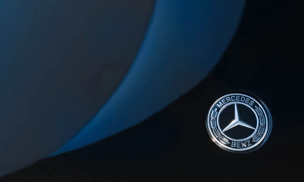 Фото Mercedes-Benz EQS (2024) — эмблема. Фирменный шильдик на кузове — знак принадлежности к марке Mercedes-Benz EQS (2024) — эмблема