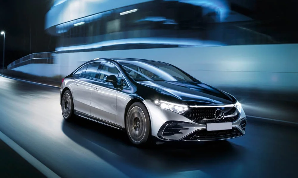 Фото Mercedes-Benz EQS (2024) — вид спереди, фото 6. Передок в серебристом исполнении — крупная светотехника и выразительный бампер. Рисунок ходовых огней — подпись модели, по нему её узнают в потоке Mercedes-Benz EQS (2024) — вид спереди, фото 6