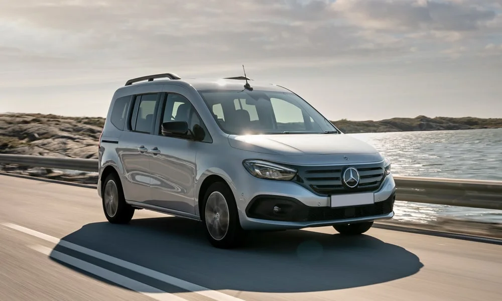 Фото Mercedes-Benz EQT (2024) — вид спереди, фото 3. Передок в серебристом исполнении — крупная светотехника и выразительный бампер. Рисунок ходовых огней — подпись модели, по нему её узнают в потоке Mercedes-Benz EQT (2024) — вид спереди, фото 3