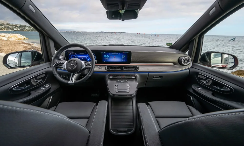 Фото Mercedes-Benz EQV (2024) — передняя панель. Передняя панель в тёмной отделке: расположение экранов и дефлекторов. Минимум физических кнопок — ставка на экранное управление Mercedes-Benz EQV (2024) — передняя панель