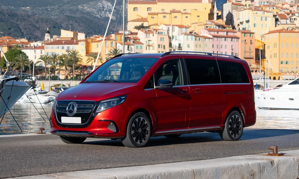 Фото Mercedes-Benz EQV (2024) — вид спереди, фото 9. Кузов в красном цвете: рисунок оптики и решётки задаёт узнаваемое «лицо» модели. Дневные ходовые огни включаются автоматически с запуском Mercedes-Benz EQV (2024) — вид спереди, фото 9