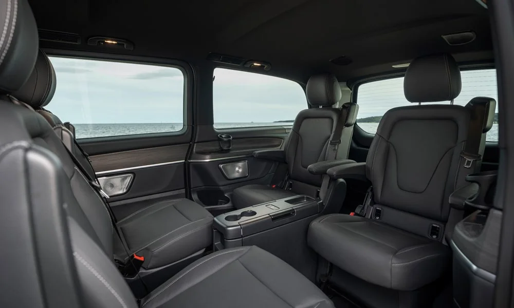 Фото Mercedes-Benz EQV (2024) — задние сиденья, фото 2. Посадка второго ряда: подголовники и подлокотник. Спинки складываются под длинные грузы у большинства версий Mercedes-Benz EQV (2024) — задние сиденья, фото 2