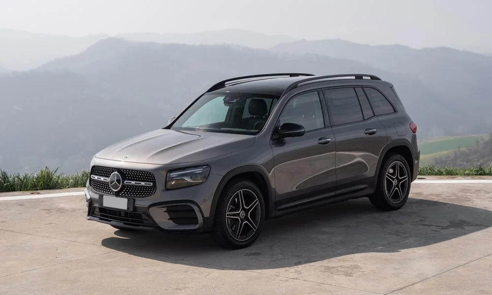 Фото Mercedes-Benz GLB (2024) — вид спереди, фото 3. Серый кузов, строгая симметрия оптики — базовый ракурс знакомства с дизайном. Дневные ходовые огни включаются автоматически с запуском Mercedes-Benz GLB (2024) — вид спереди, фото 3