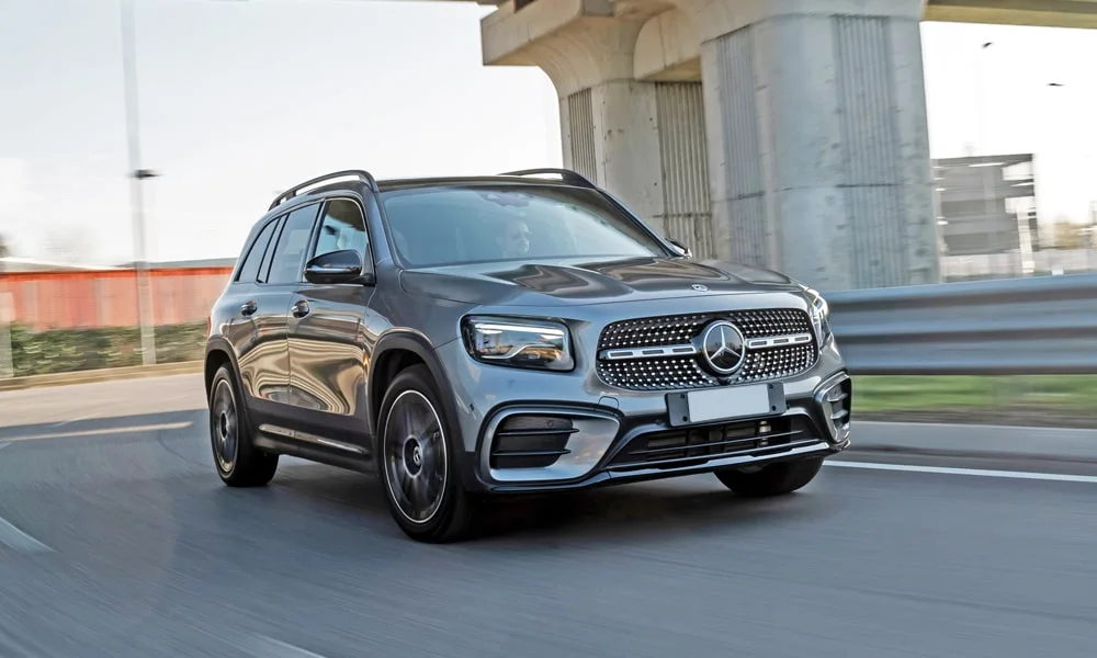 Фото Mercedes-Benz GLB (2024) — вид спереди, фото 6. Кузов в сером цвете: рисунок оптики и решётки задаёт узнаваемое «лицо» модели. Дневные ходовые огни включаются автоматически с запуском Mercedes-Benz GLB (2024) — вид спереди, фото 6