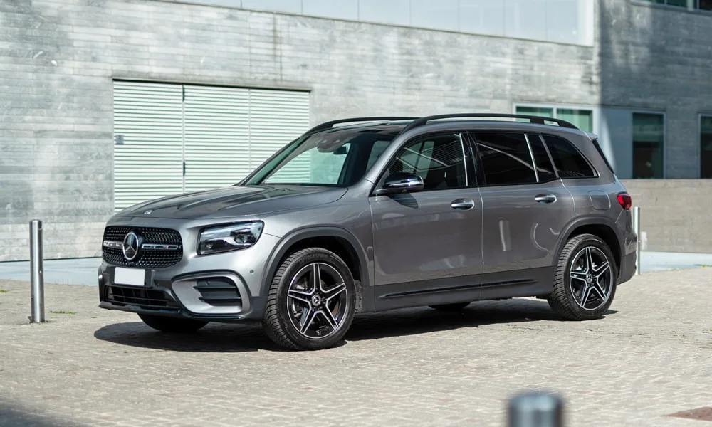 Фото Mercedes-Benz GLB (2024) — вид спереди, фото 10. Кузов в сером цвете: рисунок оптики и решётки задаёт узнаваемое «лицо» модели. Рисунок ходовых огней — подпись модели, по нему её узнают в потоке Mercedes-Benz GLB (2024) — вид спереди, фото 10