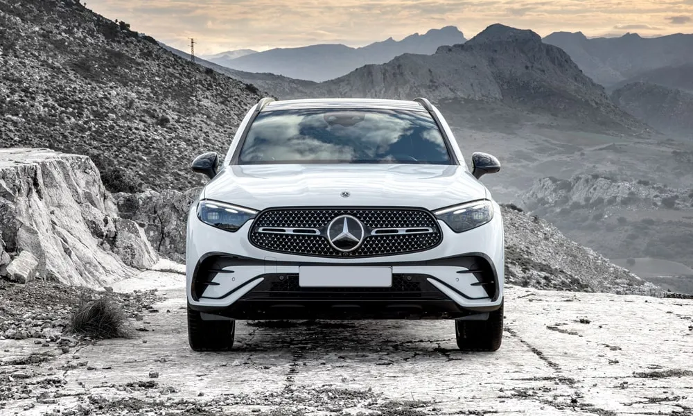 Фото Mercedes-Benz GLC (2024) — вид спереди, фото 2. Белый кузов, строгая симметрия оптики — базовый ракурс знакомства с дизайном. Рисунок ходовых огней — подпись модели, по нему её узнают в потоке Mercedes-Benz GLC (2024) — вид спереди, фото 2