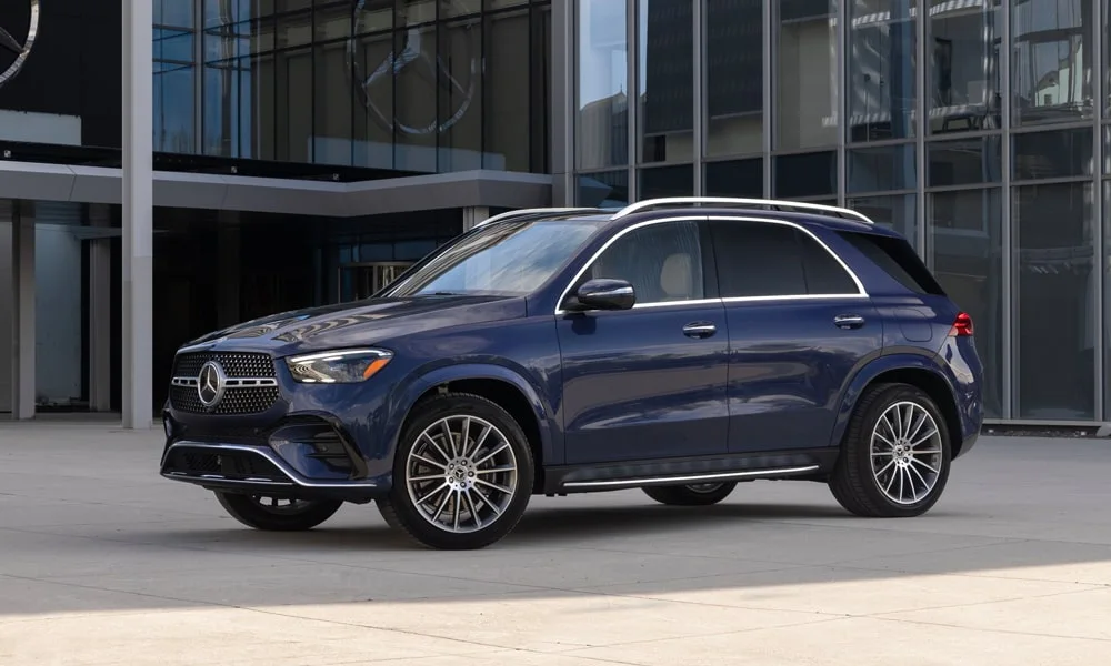 Фото Mercedes-Benz GLE (2024) — вид спереди, фото 12. Синий кузов, строгая симметрия оптики — базовый ракурс знакомства с дизайном. Рисунок ходовых огней — подпись модели, по нему её узнают в потоке Mercedes-Benz GLE (2024) — вид спереди, фото 12