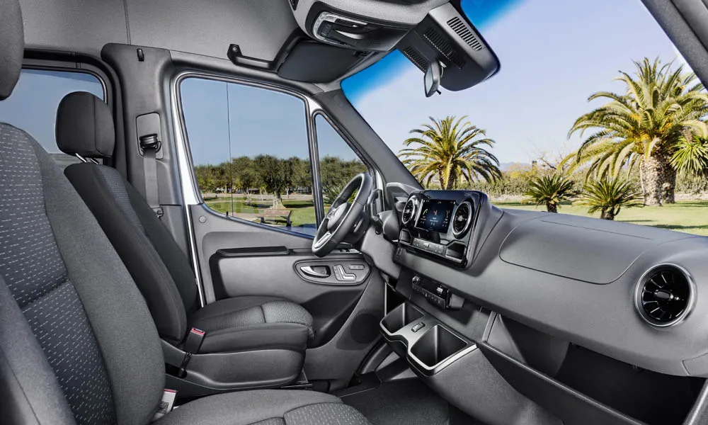 Фото Mercedes-Benz Sprinter — интерьер. Общий план салона: архитектура панели, консоль и кресла. Уровень отделки читается по стыкам панелей и мягким поверхностям в зонах касания Mercedes-Benz Sprinter — интерьер