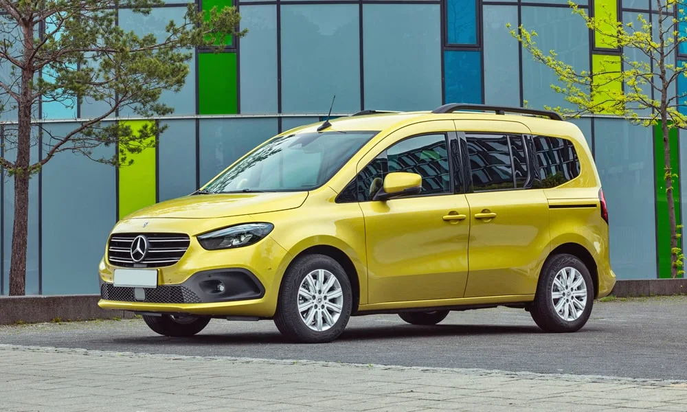 Фото Mercedes-Benz T-Class (2024) — вид спереди. Передок в жёлтом исполнении — крупная светотехника и выразительный бампер. Рисунок ходовых огней — подпись модели, по нему её узнают в потоке Mercedes-Benz T-Class (2024) — вид спереди