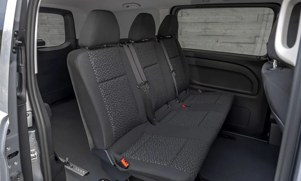Фото Mercedes-Benz Vito (2024) — задние сиденья. Задний диван в практичной ткани: посадка и центральный подлокотник. Плоский пол упрощает посадку втроём Mercedes-Benz Vito (2024) — задние сиденья