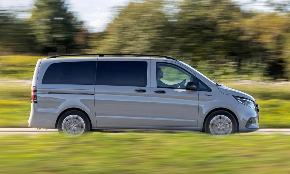 Фото Mercedes-Benz Vito (2024) — вид сбоку, фото 2. Сбоку читаются линия остекления и характер выштамповок на серебристом кузове. Длинная база — простор второго ряда; короткие свесы упрощают парковку Mercedes-Benz Vito (2024) — вид сбоку, фото 2