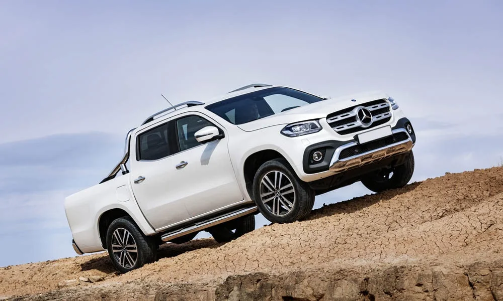 Фото Mercedes-Benz X-Class — вид спереди, фото 3. Кузов в белом цвете: рисунок оптики и решётки задаёт узнаваемое «лицо» модели. Дневные ходовые огни включаются автоматически с запуском Mercedes-Benz X-Class — вид спереди, фото 3
