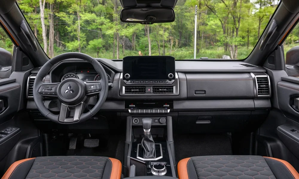 Фото Mitsubishi L200 (2024) — передняя панель. Архитектура передней панели: ярусы, вставки и консоль в тёмной гамме. Мягкие материалы верхнего яруса и вставки задают уровень интерьера Mitsubishi L200 (2024) — передняя панель