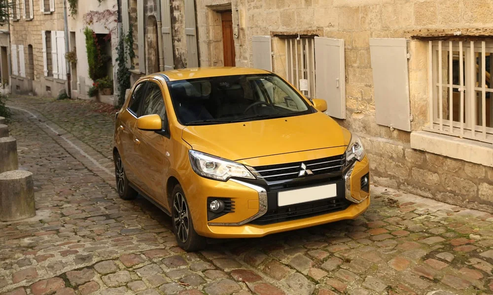 Фото Mitsubishi Space Star — вид спереди, фото 5. Жёлтый кузов, строгая симметрия оптики — базовый ракурс знакомства с дизайном Mitsubishi Space Star — вид спереди, фото 5