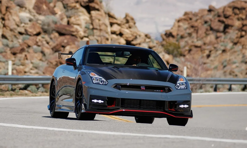 Фото Nissan GT-R — вид спереди, фото 10. Передок в сером исполнении — крупная светотехника и выразительный бампер. Рисунок ходовых огней — подпись модели, по нему её узнают в потоке Nissan GT-R — вид спереди, фото 10