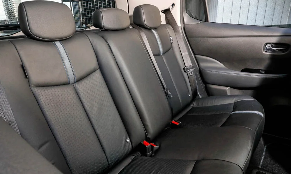 Фото Nissan Leaf — задние сиденья. Посадка второго ряда: подголовники и подлокотник. Плоский пол упрощает посадку втроём Nissan Leaf — задние сиденья
