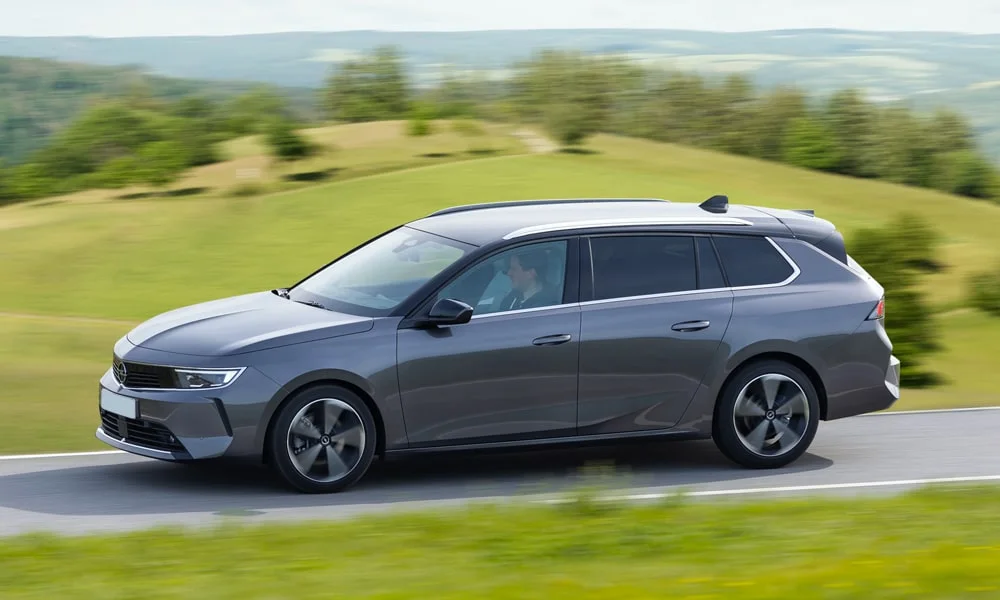 Фото Opel Astra Sports Tourer — вид сбоку, фото 3. Сбоку читаются линия остекления и характер выштамповок на сером кузове. Хромированные или чёрные молдинги окон отличают комплектации Opel Astra Sports Tourer — вид сбоку, фото 3