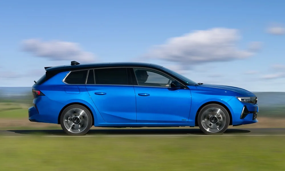 Фото Opel Astra Sports Tourer — вид сбоку, фото 7. Синий кузов в профиль — пропорции, высота посадки и дизайн дисков. Хромированные или чёрные молдинги окон отличают комплектации Opel Astra Sports Tourer — вид сбоку, фото 7
