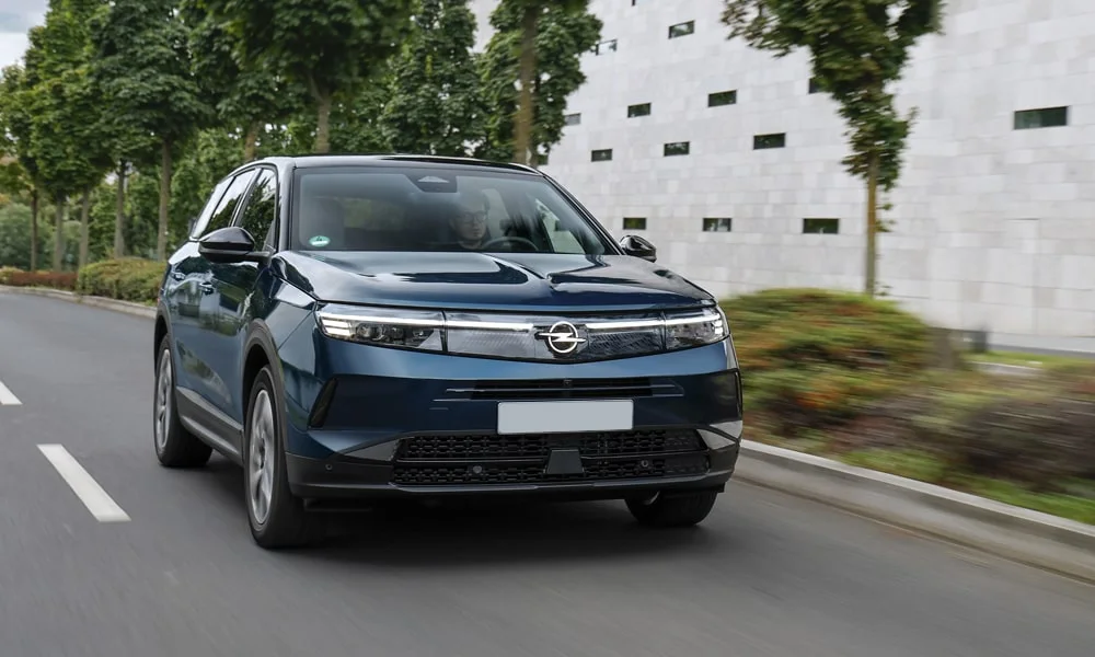 Фото Opel Grandland X (2024) — вид спереди, фото 8. Кузов в синем цвете: рисунок оптики и решётки задаёт узнаваемое «лицо» модели. Рисунок ходовых огней — подпись модели, по нему её узнают в потоке Opel Grandland X (2024) — вид спереди, фото 8