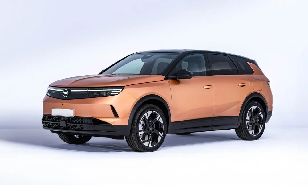 Фото Opel Grandland X (2024) — вид спереди, фото 11. Передок в оранжевом исполнении — крупная светотехника и выразительный бампер. Рисунок ходовых огней — подпись модели, по нему её узнают в потоке Opel Grandland X (2024) — вид спереди, фото 11