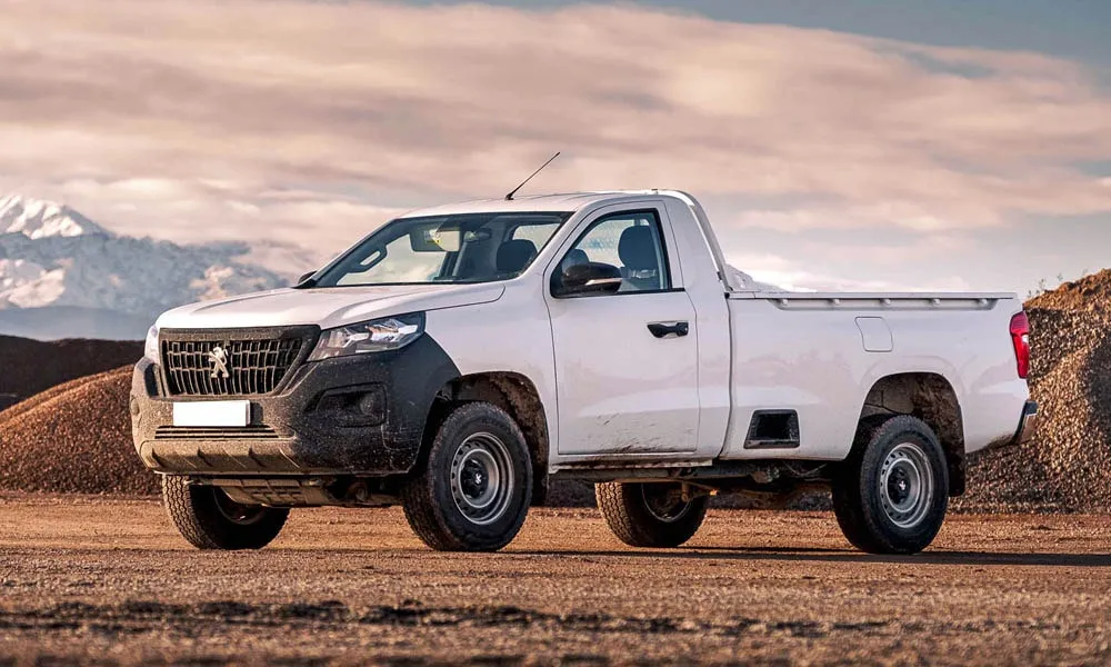 Фото Peugeot Landtrek (2024) — вид спереди, фото 6. Белый кузов, строгая симметрия оптики — базовый ракурс знакомства с дизайном. Рисунок ходовых огней — подпись модели, по нему её узнают в потоке Peugeot Landtrek (2024) — вид спереди, фото 6
