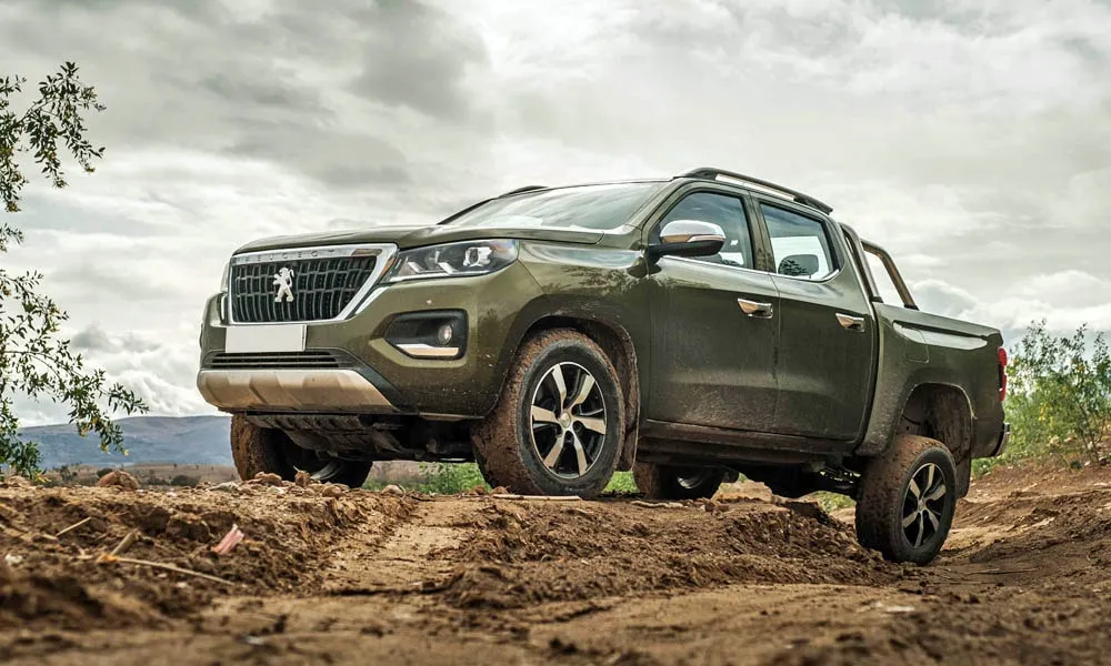 Фото Peugeot Landtrek (2024) — вид спереди, фото 13. Кузов в зелёном цвете: рисунок оптики и решётки задаёт узнаваемое «лицо» модели. Рисунок ходовых огней — подпись модели, по нему её узнают в потоке Peugeot Landtrek (2024) — вид спереди, фото 13