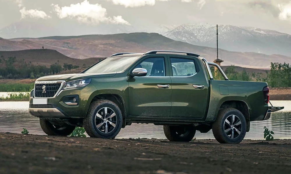 Фото Peugeot Landtrek (2024) — вид спереди, фото 15. Кузов в зелёном цвете: рисунок оптики и решётки задаёт узнаваемое «лицо» модели. Рисунок ходовых огней — подпись модели, по нему её узнают в потоке Peugeot Landtrek (2024) — вид спереди, фото 15