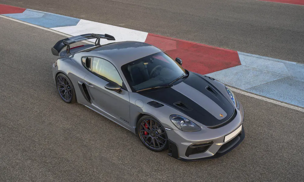 Фото Porsche 718 Cayman GT4 RS (2024) — вид спереди, фото 4. Серый кузов, строгая симметрия оптики — базовый ракурс знакомства с дизайном. Рисунок ходовых огней — подпись модели, по нему её узнают в потоке Porsche 718 Cayman GT4 RS (2024) — вид спереди, фото 4