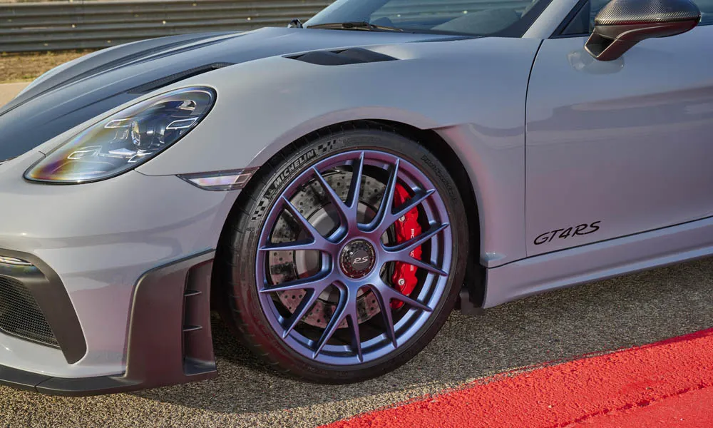 Фото Porsche 718 Cayman GT4 RS (2024) — вид спереди, фото 6. Кузов в сером цвете: рисунок оптики и решётки задаёт узнаваемое «лицо» модели. Рисунок ходовых огней — подпись модели, по нему её узнают в потоке Porsche 718 Cayman GT4 RS (2024) — вид спереди, фото 6