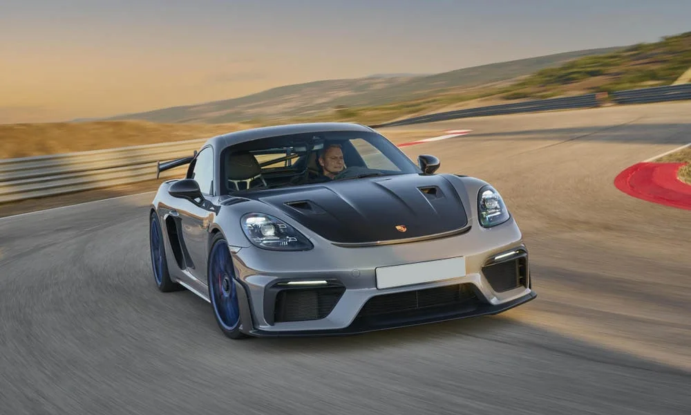 Фото Porsche 718 Cayman GT4 RS (2024) — вид спереди, фото 7. Кузов в сером цвете: рисунок оптики и решётки задаёт узнаваемое «лицо» модели. Дневные ходовые огни включаются автоматически с запуском Porsche 718 Cayman GT4 RS (2024) — вид спереди, фото 7
