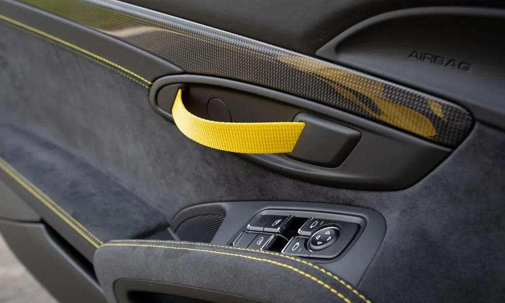 Фото Porsche 718 Cayman GT4 — дверная карта, фото 2. Дверная карта в тёмной отделке: подлокотник, динамик и блок стеклоподъёмников Porsche 718 Cayman GT4 — дверная карта, фото 2