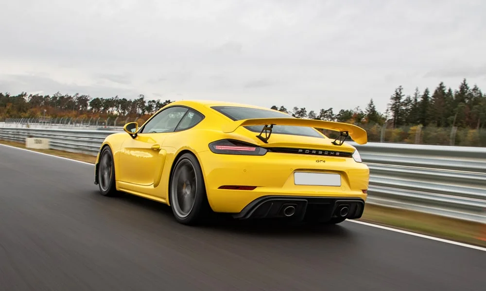 Фото Porsche 718 Cayman GT4 — вид сзади, фото 8. Жёлтый кузов сзади — фонари и бампер определяют ночной образ модели Porsche 718 Cayman GT4 — вид сзади, фото 8