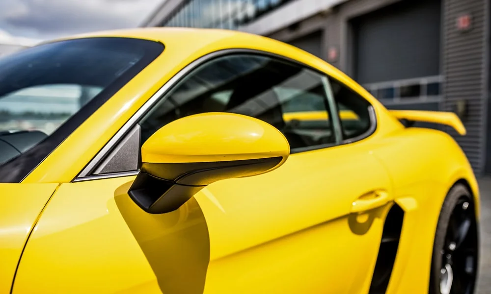 Фото Porsche 718 Cayman GT4 — вид сбоку, фото 3. Профиль кузова: колёсная база, свесы и линия остекления. Хромированные или чёрные молдинги окон отличают комплектации Porsche 718 Cayman GT4 — вид сбоку, фото 3